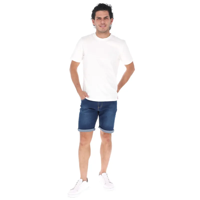 Hombre vistiendo camiseta blanca y shorts de mezclilla.